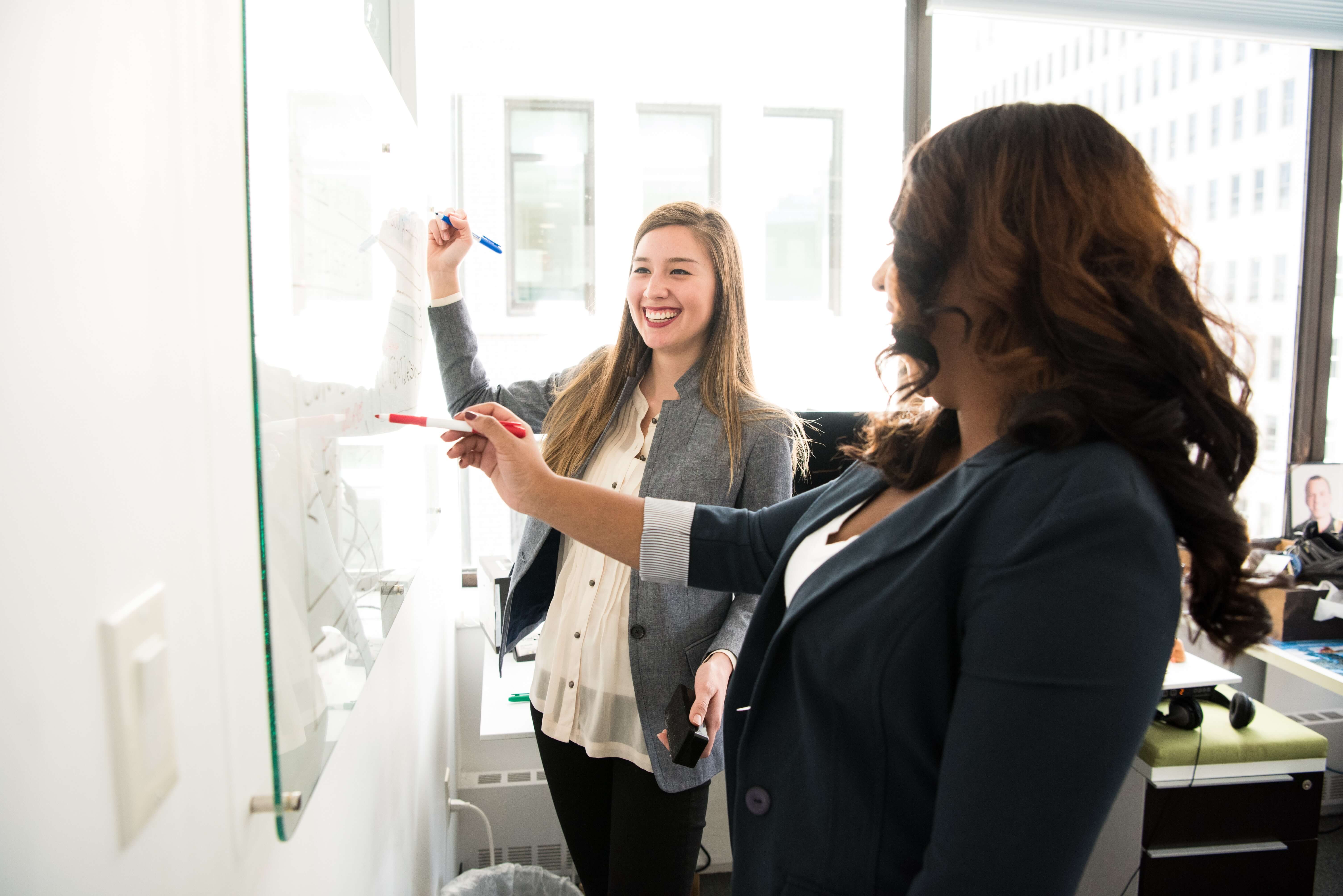 Two smiling business people giving a presentation in front of a whiteboard